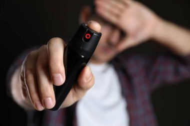 Elle gözlerini kapatan ve siyah arka planda biber gazı kullanan adam, teneke kutuya odaklan.