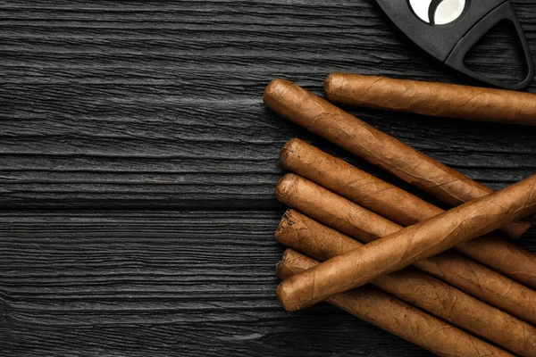 Puro ve giyotin makası siyah ahşap masada, düz yerde. Metin için boşluk