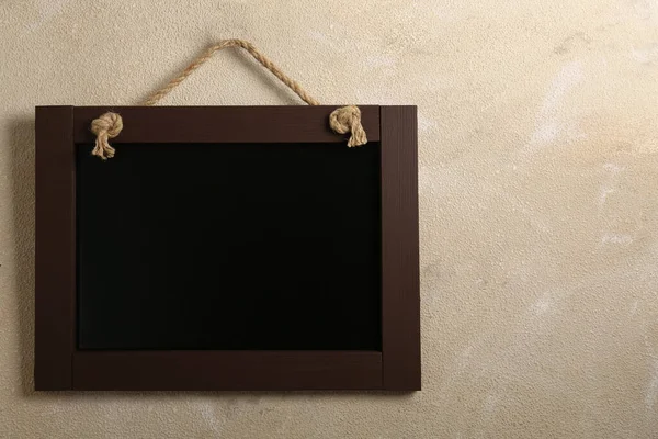 Bej duvarda asılı temiz, küçük siyah karatahta, metin için boşluk