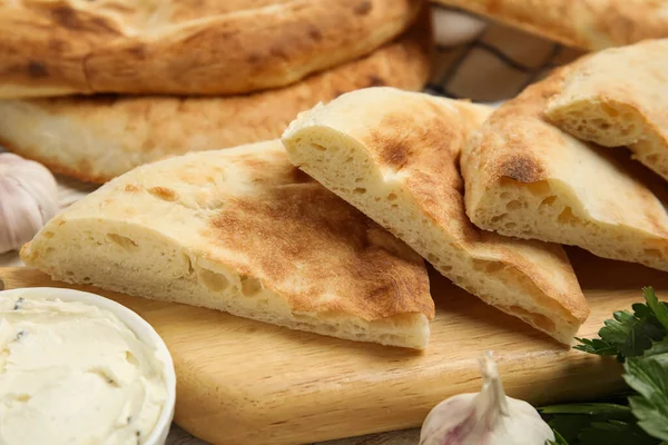Masanın üzerinde taze pita ekmek ve krem peynir parçaları, yakın plan.