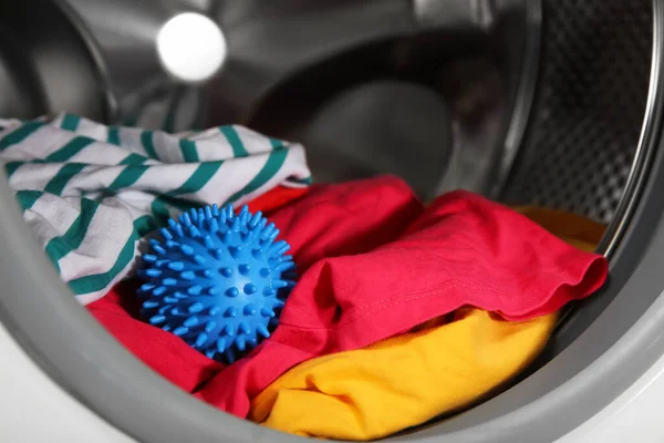 洗濯機のドラムの青いドライヤーボールと服 クローズアップ — ストック写真