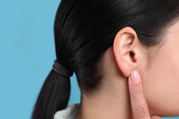 Wanita Menunjuk Telinganya Pada Latar Belakang Biru Muda Closeup — Stok Foto