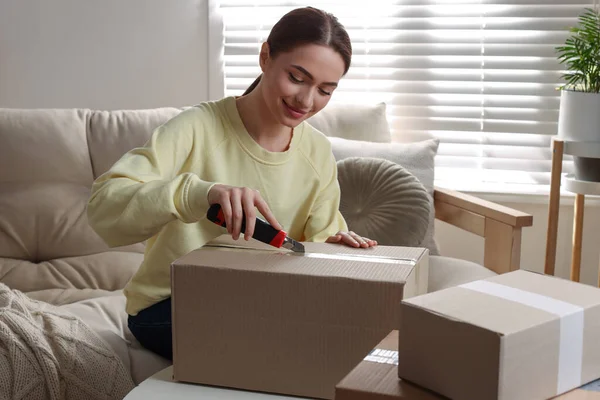 Ung Kvinna Använder Verktygskniv För Att Öppna Paket Hemma — Stockfoto