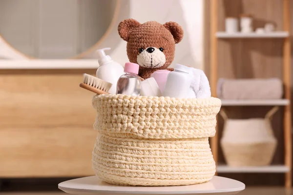 室内白桌上有婴儿化妆品 浴具和玩具熊的编织篮子 — 图库照片