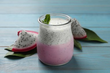 Lezzetli pitahaya smoothie, meyve ve açık mavi ahşap masada taze nane.