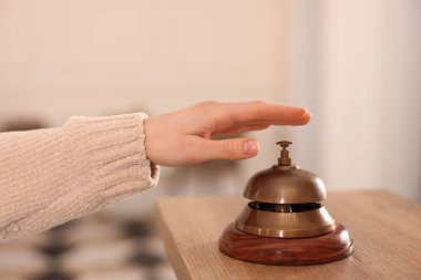Ahşap resepsiyonda otelin servis zilini çalan kadın, yakın plan.