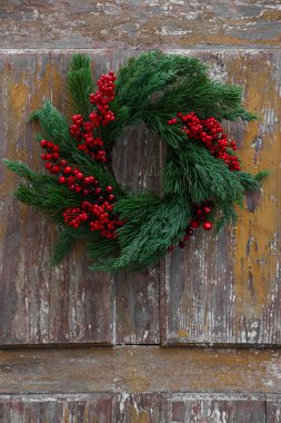 Ahşap duvarda kırmızı böğürtlenli güzel Noel çelengi