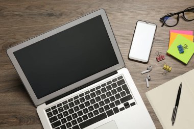 Modern dizüstü bilgisayar, akıllı telefon ve ofis kırtasiyesi ahşap masada, düz konum. Uzaklık öğrenimi