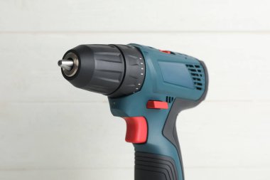 Beyaz ahşap duvarın yanında modern elektrikli matkap, yakın plan.