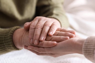 Genç ve yaşlı kadınların el ele tutuşması, yakın çekim.