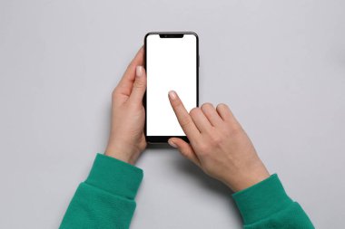 Açık gri arka planda akıllı telefon kullanan kadın, üst görünüm