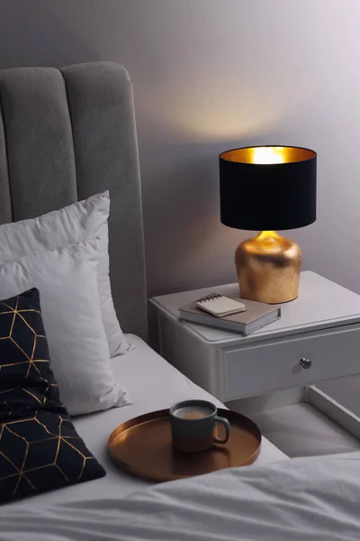スタイリッシュなランプとベッドサイドテーブルの上の本室内 寝室のインテリア要素 — ストック写真