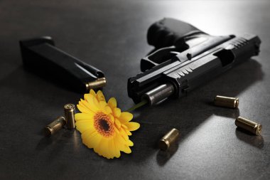 Güzel çiçek, mermiler ve tabanca gri masada. Savaş yerine barış