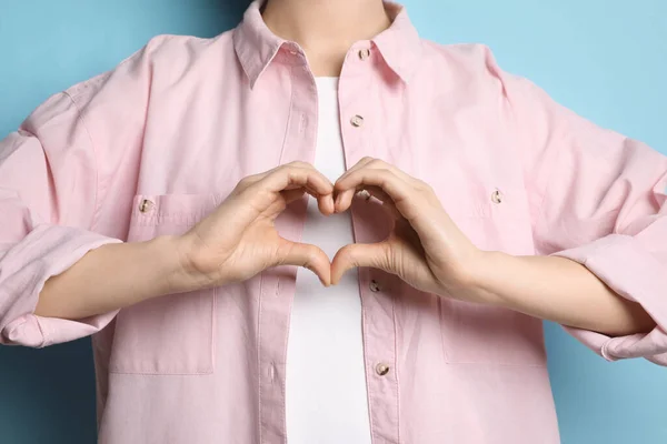 Mujer Haciendo Corazón Con Las Manos Sobre Fondo Azul Claro —  Fotos de Stock