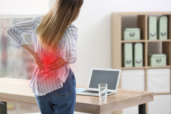 Woman suffering from back pain in office. Symptom of bad posture