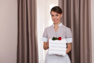 Otel odasında bir yığın temiz havlusu olan güzel oda hizmetçisi.