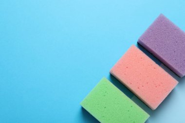 Açık mavi arka planda yeni süngerler, düz yatış. Metin için boşluk