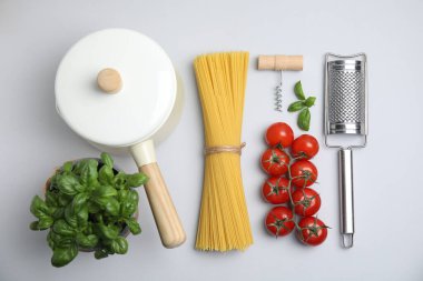 Beyaz arka planda pişmemiş spagetti ve pişirme aletleri ile kompozisyon, üst görünüm