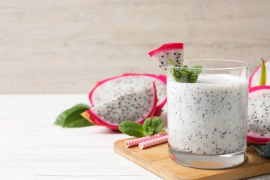 Bir bardak lezzetli pitahaya smoothie beyaz ahşap masa üzerinde taze nane ile, metin için yer