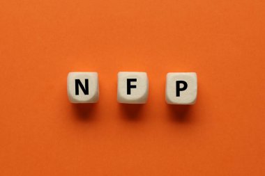 Turuncu arkaplanda harfleri olan küplerden yapılan kısaltma NFP (Çiftlik Dışı Maaş bordrosu)