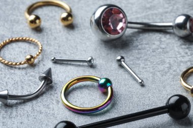 Açık gri masadaki piercing mücevherleri, yakın plan.