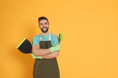 Turuncu arkaplanda fırça ve faraş olan adam, metin için boşluk