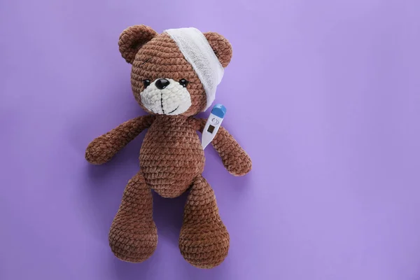 Toy Bear Bandage Thermometer Violet Background Top View Space Text — Foto Stock