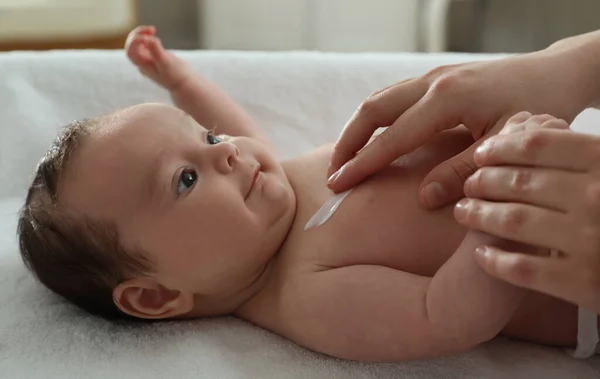 Ibu Mengoleskan Krim Tubuh Pada Bayi Kecilnya Dalam Ruangan — Stok Foto