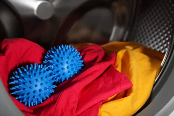 洗濯機のドラムの青いドライヤーボールと服 クローズアップ — ストック写真