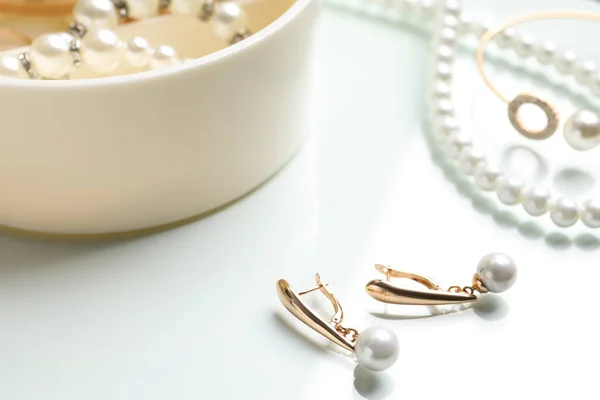 精致的金耳环和其他时尚珠宝 白色桌子上有珍珠 — 图库照片