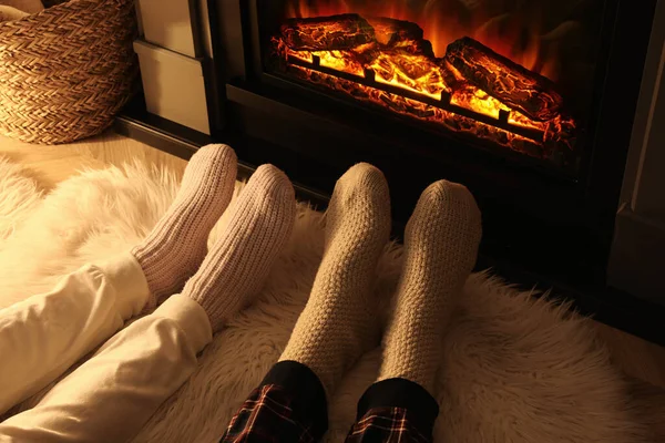 Evde şöminenin yanında çorap ören çift, bacaklarına yakın.