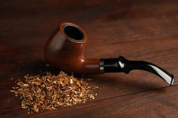 Pile of tobacco and smoking pipe on wooden table