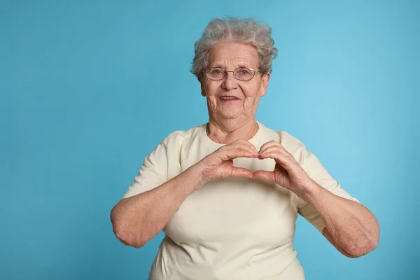 Elderly Woman Making Heart Her Hands Light Blue Background Space — 스톡 사진