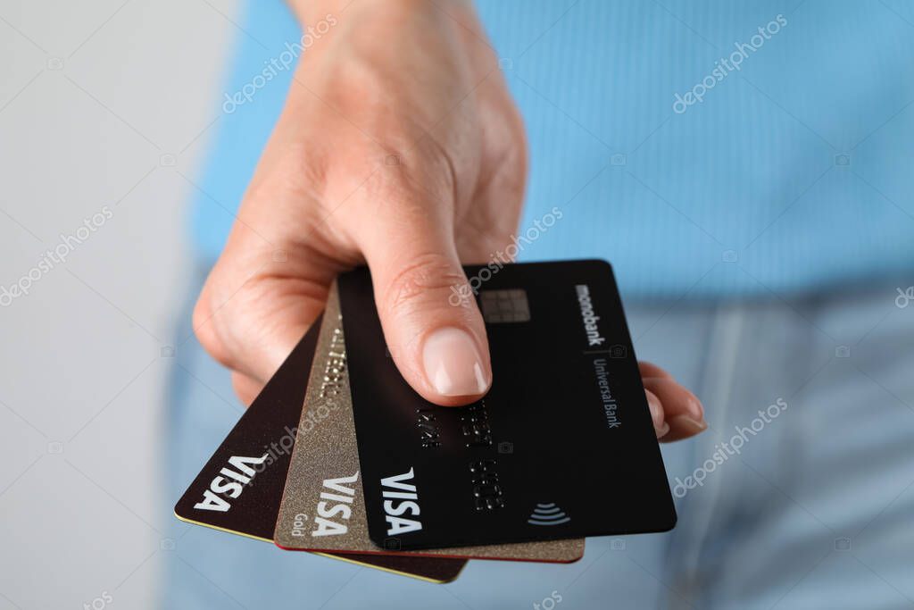 MYKOLAIV, UKRAINE - FEBRUARY 22, 2022: Woman holding Visa credit cards on white background, closeup