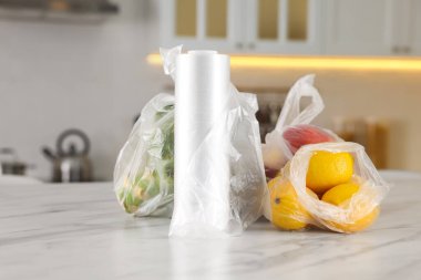 Mutfaktaki beyaz mermer masada farklı taze ürünlerin olduğu plastik torbalar.