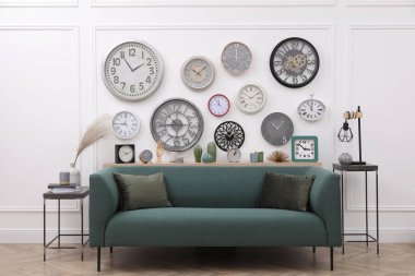 Farklı saat koleksiyonu ve şık bir odada rahat bir kanepe. İç tasarım