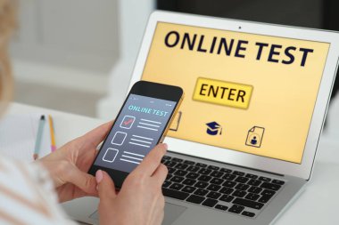İçerideki masada akıllı telefondan çevrimiçi test yaptıran kadın, yakın plan.
