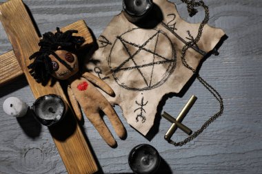Gri ahşap masada kalbi ve törensel eşyaları olan kadın voodoo bebeği.