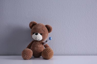 Beyaz masasında termometresi olan sevimli oyuncak ayı, mesaj için yer var. Çocuk Hastanesi