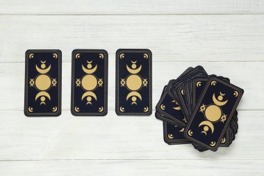 Tarot kartları beyaz ahşap masada, düz yerde. Ters taraf