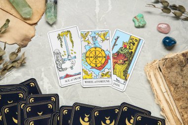 Üzerinde değerli taşlar olan tarot kartları ve gri masa üzerinde eski kitap, düz yatıyordu.