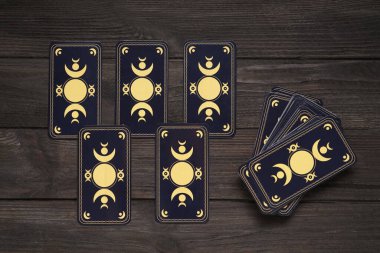 Tarot kartları siyah ahşap masada, düz yerde. Ters taraf