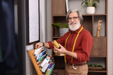 Atölyenin yanında iplik seçen profesyonel bir terzi