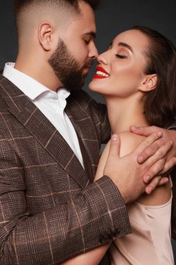 Gri arka planda seksi bayan olan yakışıklı sakallı adam.
