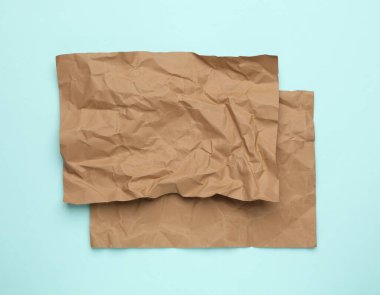 Açık mavi zemin üzerinde buruşuk kahverengi kağıtlar, üst görünüm