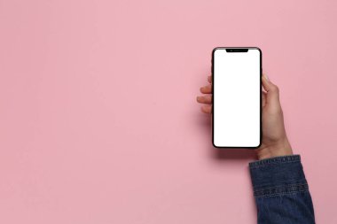 Pembe arka planda akıllı telefonu olan bir kadın. Metin için boşluk