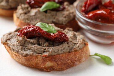 Lezzetli ezmeli ekmek dilimleri, kurutulmuş domates ve peçeteli fesleğen, yakın plan.