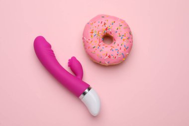 Vajinal vibratör ve donut pembe arka planda, düz yerde. Seks oyuncağı