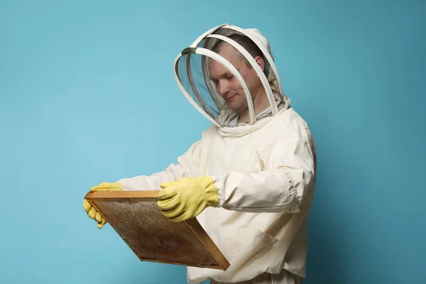養蜂家で均一な保持じんましんフレームとともにハニカムオンライトブルーの背景 — ストック写真