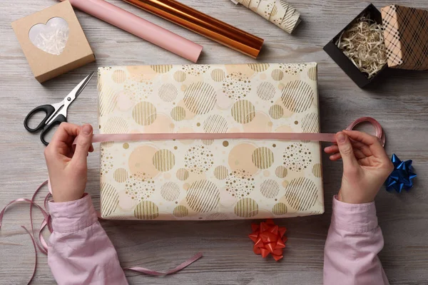 Beyaz ahşap masada Noel hediyesi sarma kadın, üst görünümü